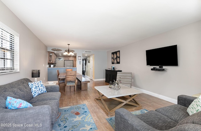 living room featuring a chandelier, light wood finished floors, and baseboards