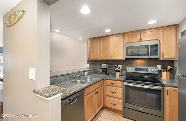 kitchen with appliances with stainless steel finishes, a sink, dark stone counters, tasteful backsplash, and recessed lighting