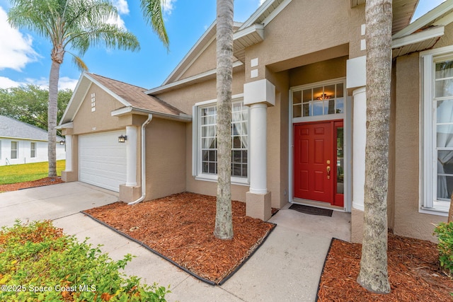 2100 Weatherly Ave, Melbourne, FL 32904 - doorway to property with an attached garage, stucco siding, and concrete driveway