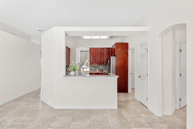2100 Weatherly Ave, Melbourne, FL 32904 - kitchen with backsplash, refrigerator, light countertops, light tile patterned floors, and reddish brown cabinets