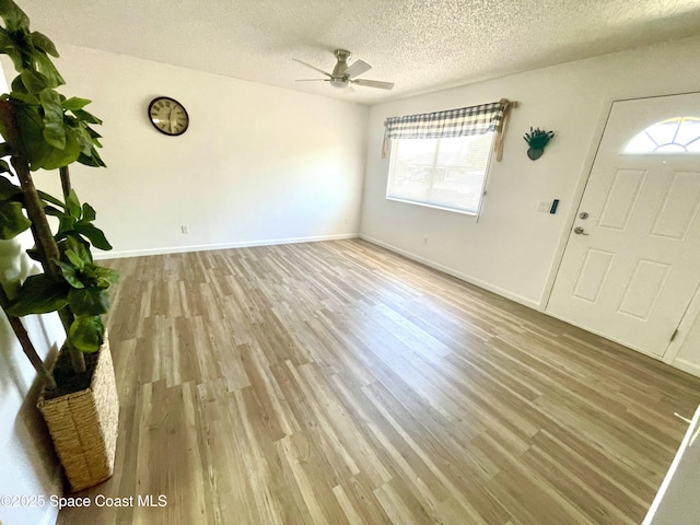entrance foyer featuring a textured ceiling, ceiling fan, wood finished floors, and baseboards