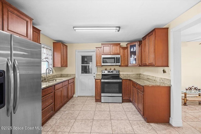 15 Skyline Blvd, Merritt Island, FL 32953 - kitchen featuring stainless steel appliances, a sink, light stone counters, glass insert cabinets, and brown cabinets
