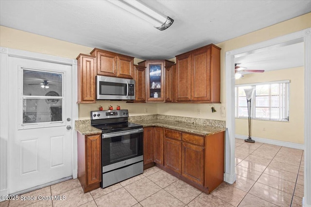 15 Skyline Blvd, Merritt Island, FL 32953 - kitchen with appliances with stainless steel finishes, a ceiling fan, light tile patterned flooring, and brown cabinetry