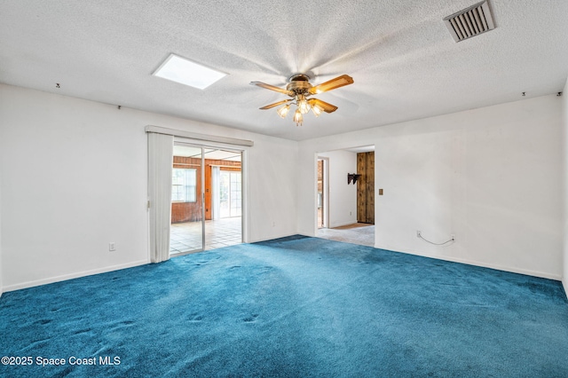 carpeted empty room featuring baseboards, ceiling fan, a textured ceiling, and visible vents