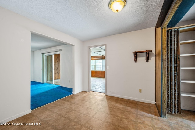 empty room featuring a textured ceiling and baseboards