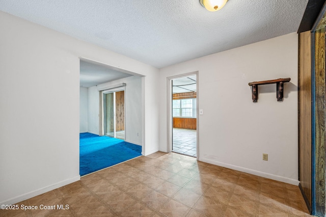 unfurnished room with baseboards and a textured ceiling