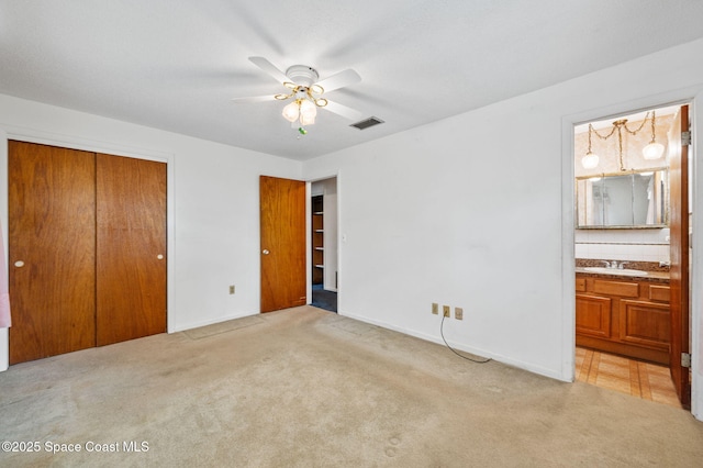 unfurnished bedroom featuring a closet, a sink, visible vents, and carpet flooring