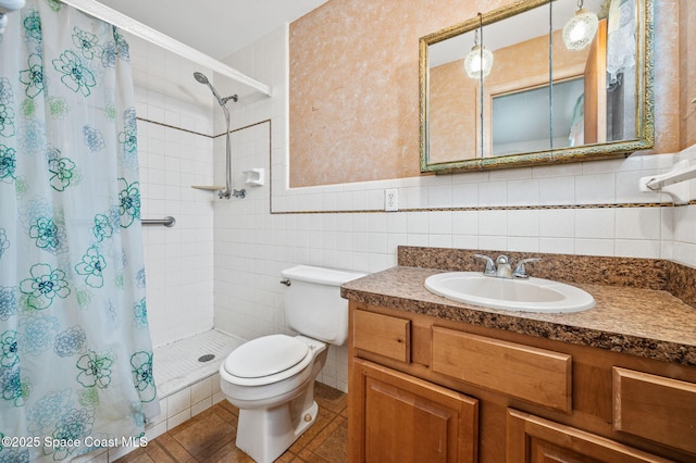 bathroom with tile walls, a stall shower, vanity, tile patterned floors, and toilet