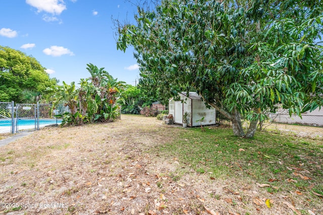 view of yard with a fenced backyard, a fenced in pool, an outdoor structure, and a shed