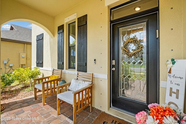 view of exterior entry featuring a porch and stucco siding