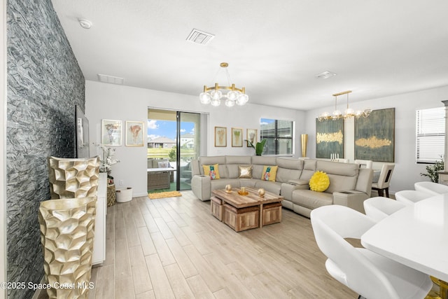 living room featuring light wood finished floors, a chandelier, and visible vents
