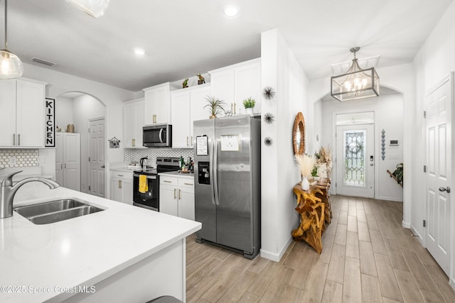 kitchen featuring a sink, visible vents, arched walkways, light countertops, and appliances with stainless steel finishes