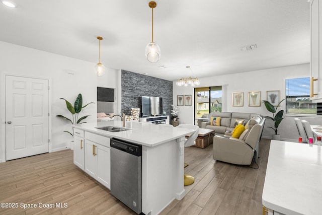 kitchen featuring dishwasher, visible vents, a sink, open floor plan, and light wood-style floors