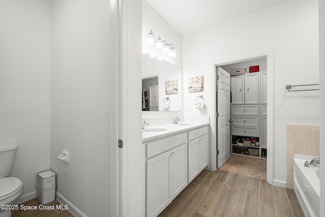 full bathroom with a sink, toilet, wood finished floors, double vanity, and a bath