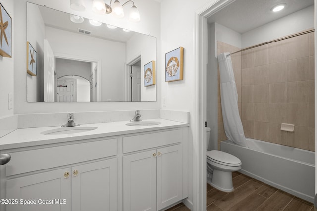 bathroom featuring toilet, visible vents, a sink, and wood finished floors