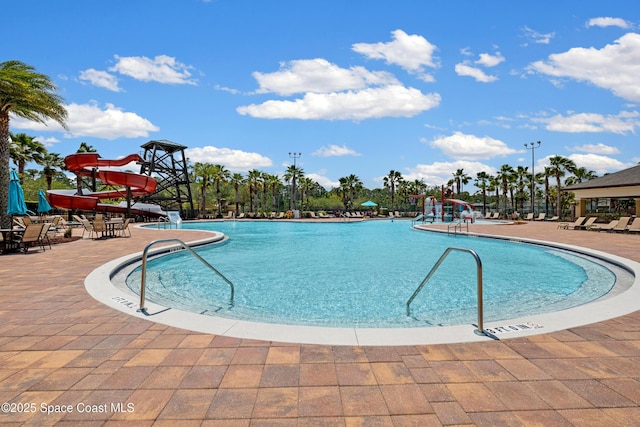 community pool with a patio and a water slide