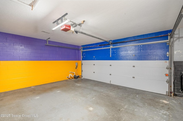 garage with concrete block wall and a garage door opener