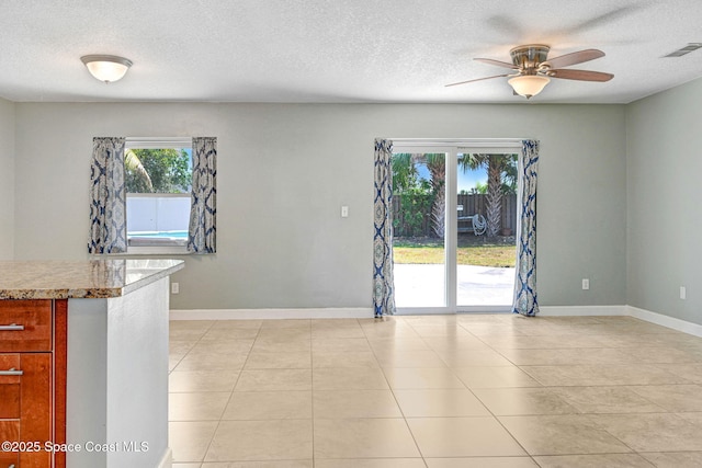 empty room featuring visible vents, baseboards, ceiling fan, a textured ceiling, and light tile patterned floors