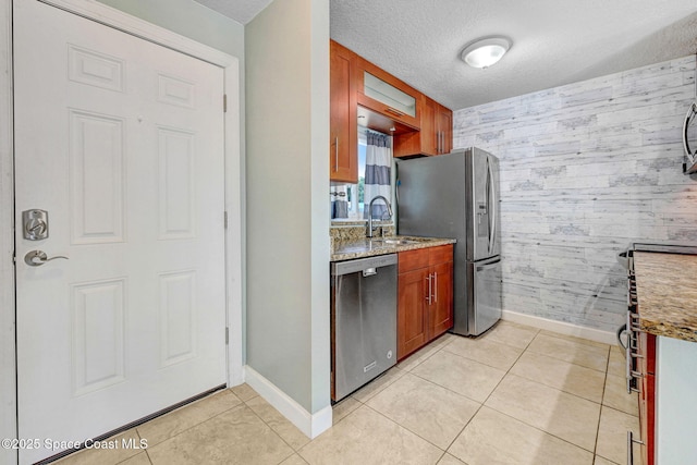 kitchen with baseboards, an accent wall, stainless steel appliances, and wallpapered walls
