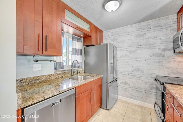 kitchen featuring stainless steel appliances, light stone countertops, and a sink
