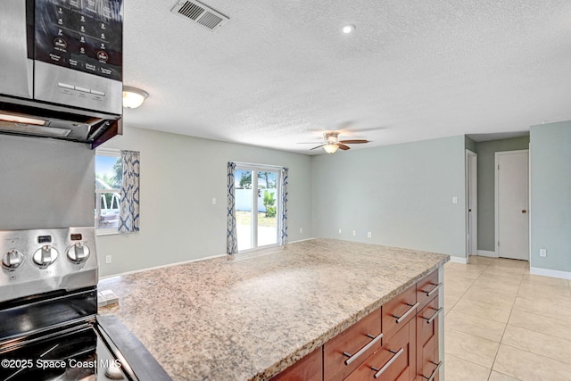 kitchen featuring a ceiling fan, a textured ceiling, visible vents, brown cabinets, and stainless steel appliances