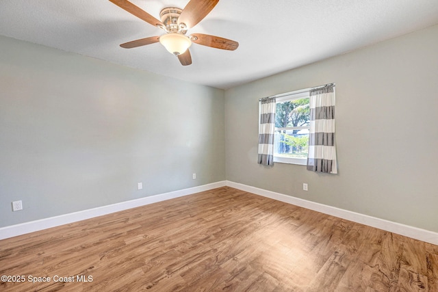 empty room with baseboards, a ceiling fan, and wood finished floors