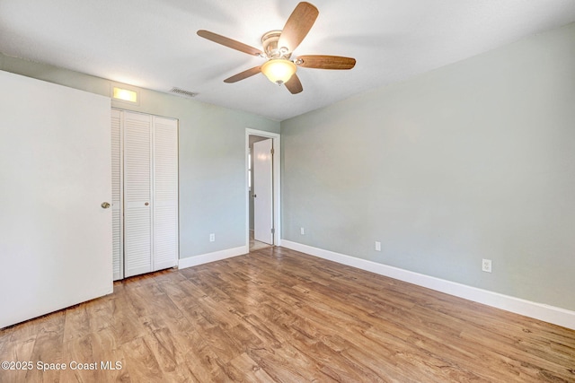 unfurnished bedroom with a ceiling fan, baseboards, wood finished floors, visible vents, and a closet