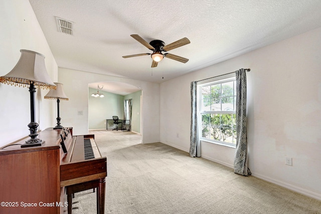 interior space with carpet floors, ceiling fan with notable chandelier, arched walkways, and visible vents