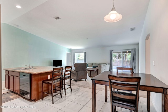 interior space with an island with sink, a sink, pendant lighting, open floor plan, and light countertops