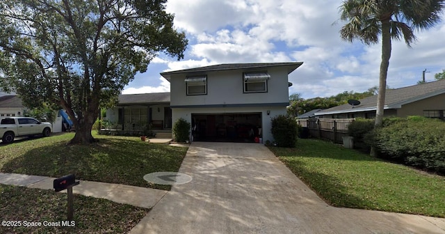 view of front of house featuring driveway, fence, a front yard, stucco siding, and a garage