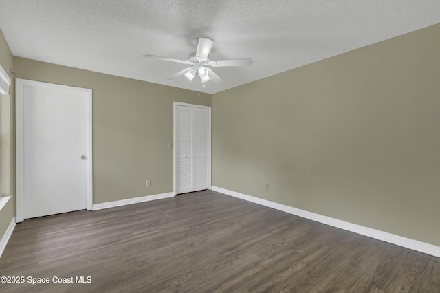 unfurnished bedroom with dark wood-style flooring, baseboards, and a textured ceiling