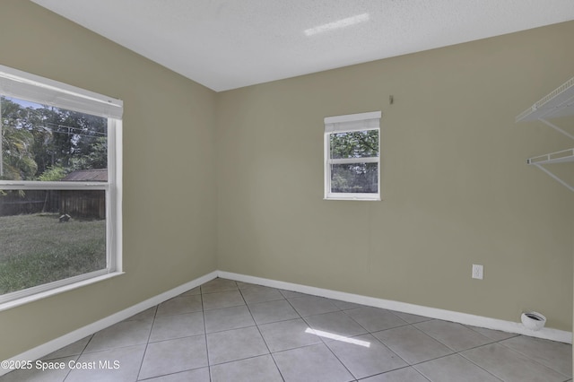 tiled spare room featuring baseboards