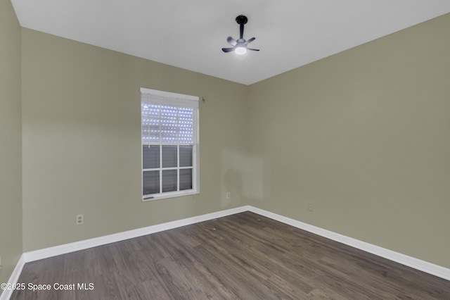 empty room with baseboards, ceiling fan, and dark wood finished floors