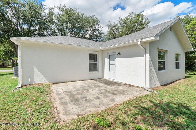 1500 Gardenton St NW Unit 44, Palm Bay, FL 32907 - rear view of house with a yard, a patio, stucco siding, roof with shingles, and central air condition unit