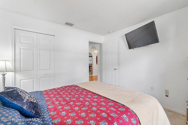 1500 Gardenton St NW Unit 44, Palm Bay, FL 32907 - bedroom with light carpet, arched walkways, a closet, a textured ceiling, and baseboards