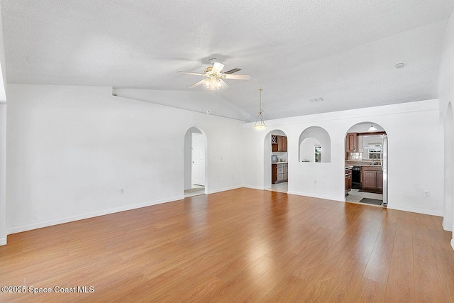 1500 Gardenton St NW Unit 44, Palm Bay, FL 32907 - unfurnished living room featuring arched walkways, a ceiling fan, light wood-style flooring, vaulted ceiling, and a textured ceiling
