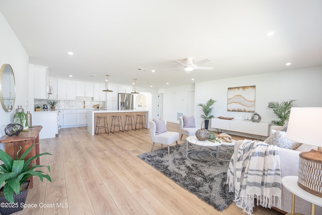 living area featuring ceiling fan, light wood finished floors, and recessed lighting
