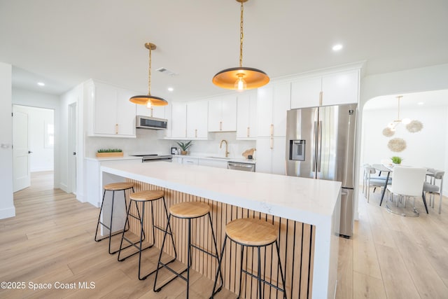 kitchen featuring light countertops, white cabinetry, appliances with stainless steel finishes, and light wood-style flooring