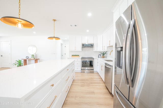 kitchen featuring a kitchen island, recessed lighting, a sink, light wood finished floors, and stainless steel appliances