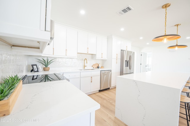 kitchen with a sink, a kitchen breakfast bar, stainless steel appliances, a kitchen island, and visible vents