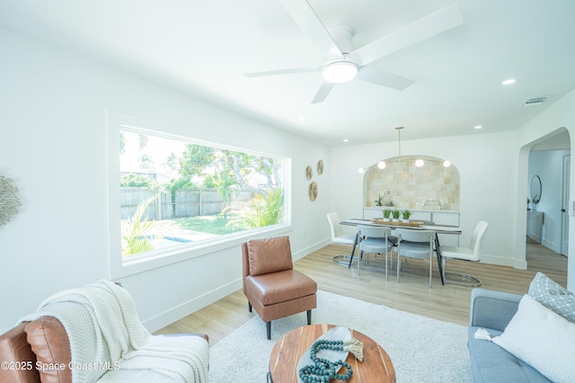 living room featuring arched walkways, recessed lighting, baseboards, wood finished floors, and visible vents