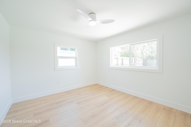 spare room with baseboards, ceiling fan, wood finished floors, and a wealth of natural light
