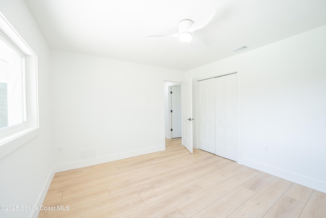 empty room with baseboards, ceiling fan, wood finished floors, and visible vents