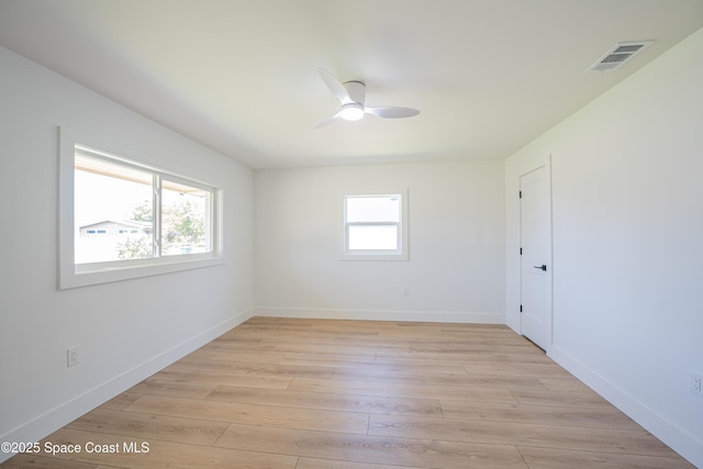 empty room with light wood-style floors, baseboards, a ceiling fan, and visible vents