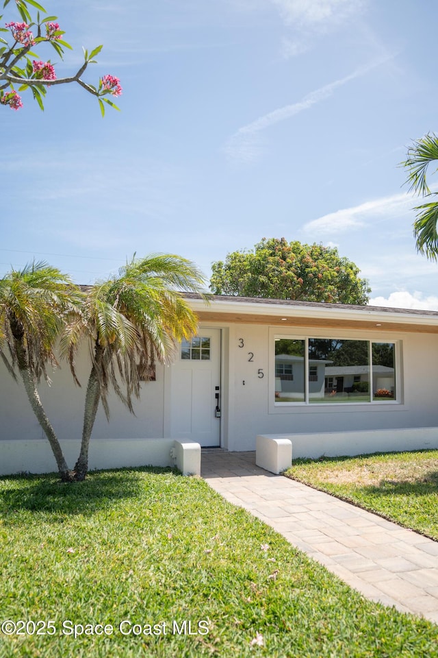 single story home with stucco siding and a front lawn