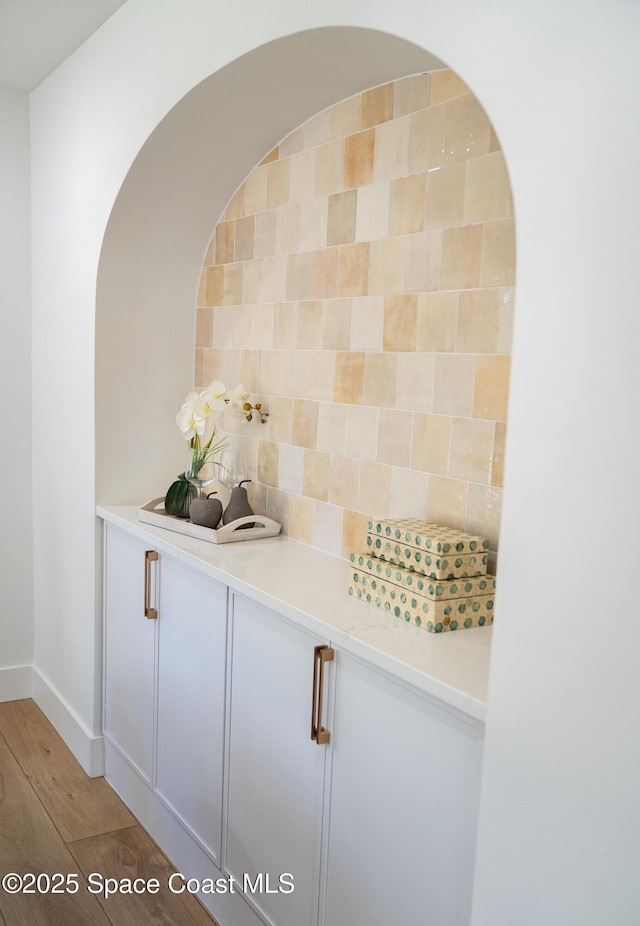 interior space with backsplash, baseboards, and light wood-type flooring