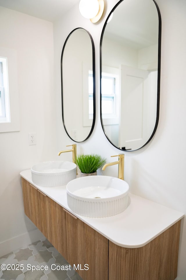 bathroom featuring a sink, baseboards, and double vanity