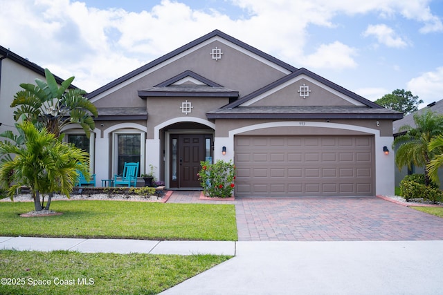 993 Musgrass Cir, West Melbourne, FL 32904 - view of front of house featuring stucco siding, a front lawn, a garage, and decorative driveway