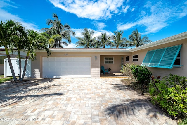 single story home featuring brick siding, decorative driveway, and an attached garage