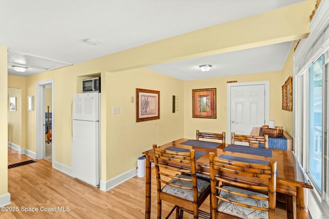 dining area with light wood-style floors, baseboards, and visible vents